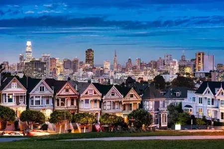 The famous Painted Ladies of Alamo Square are pictured before The San Francisco skyline at twilight.