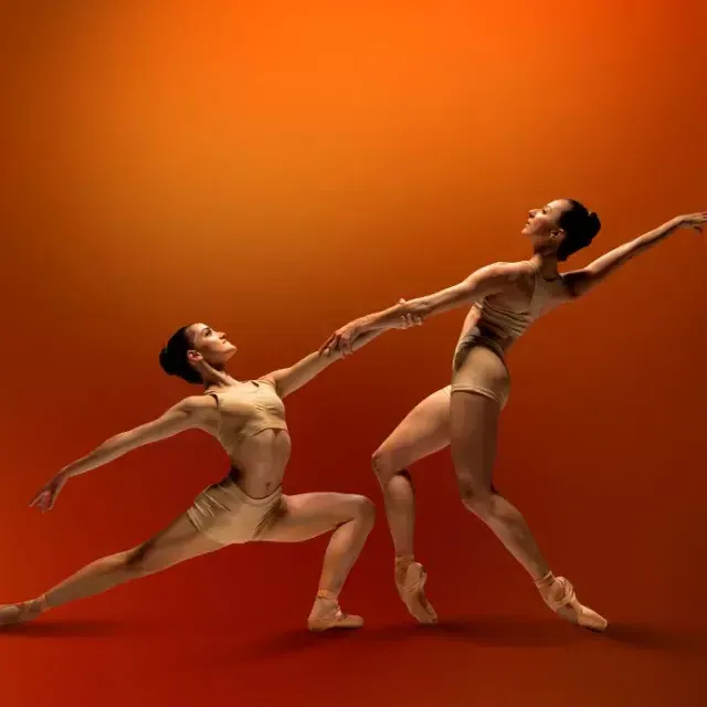 SF ballet dancers holding hands on a red background 